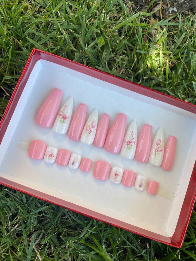 Long almond press-on nail set with pink base and white floral accent nails in red gift box